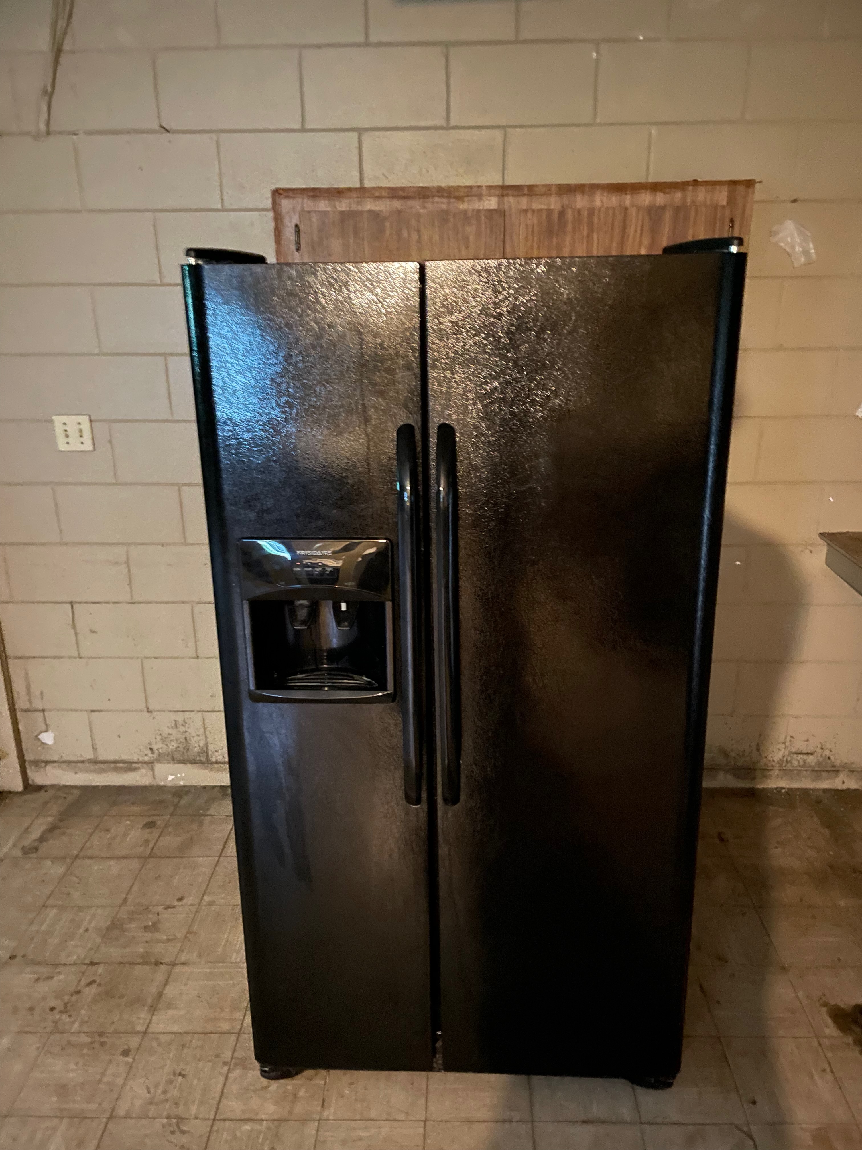 Black side-by-side refrigerator pulled out for appliance removal