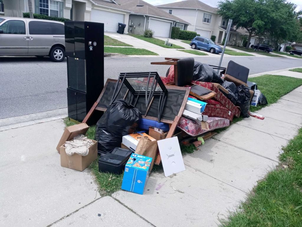 Curbside furniture and appliance pile ready for junk pickup